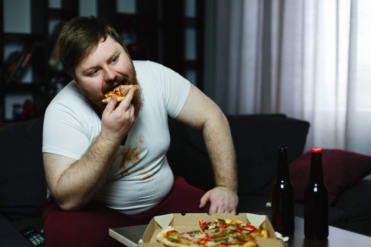 Homme en surpoids qui mange une pizza